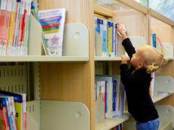 Little girl reaching for books.